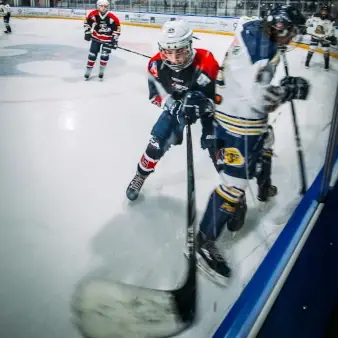 Eishockey Nachwuchsspieler kämpfen an der Bande um den Puck